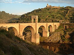 Ponte de arco de pedra atravessando um vale